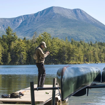 Fly Fisherman getting his gear ready on the dock at Kidney Pond in Baxter State Park, Maine